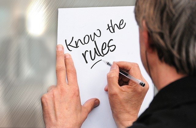Persona escribiendo en un papel "know the rules"
