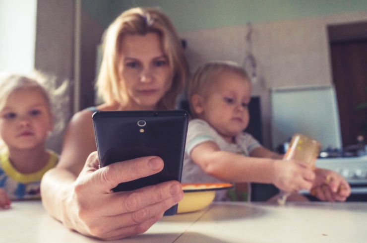 woman holding 2 kids and on phone to show multitasking