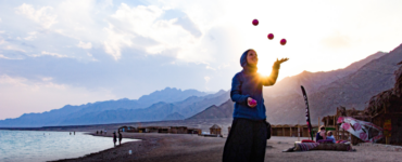 woman juggling 3 balls at a beach
