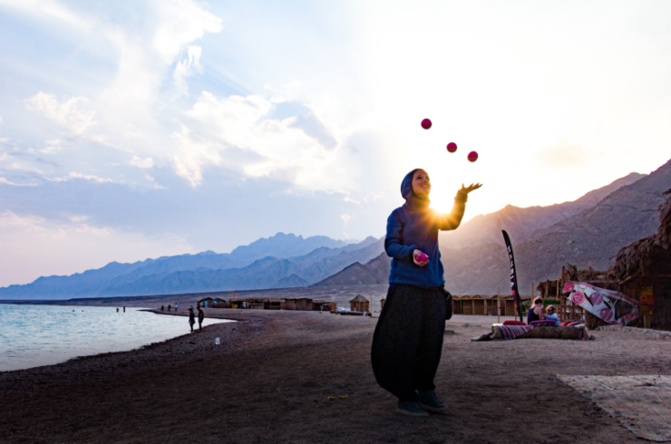woman juggling 3 balls at a beach