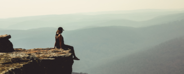 woman sitting on edge of cliff